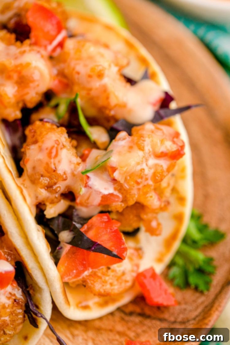 Close up photo of bang bang shrimp tacos on a wooden plate.