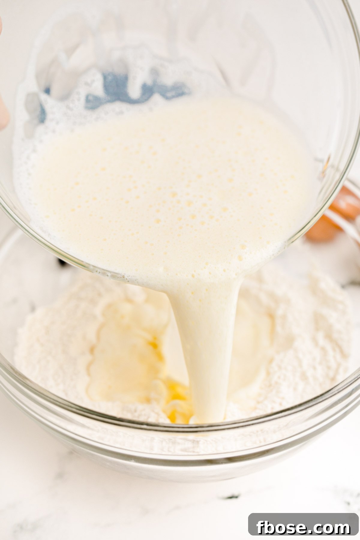 Egg and milk mixture being poured into dry ingredients to make blueberry pancakes.