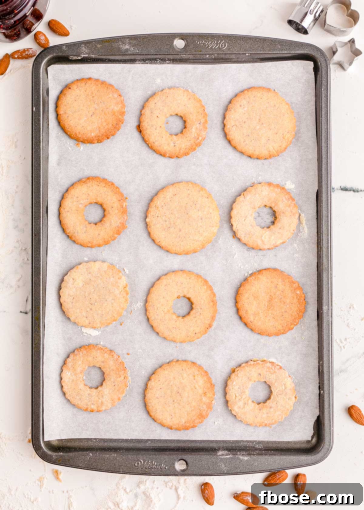 Berry-Filled Linzer Delights 12 Linzer cookies on a parchment lined baking sheet.