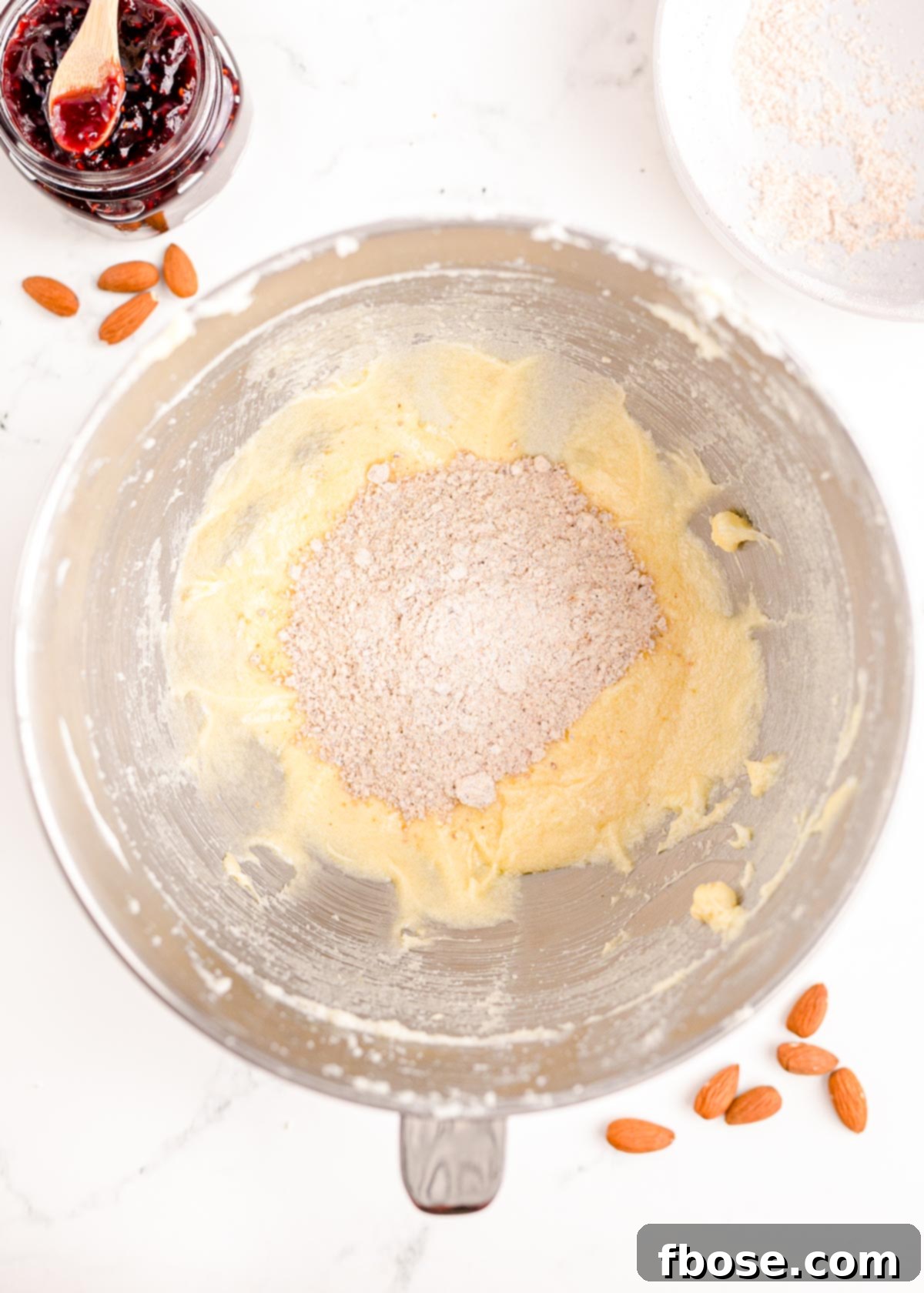Berry-Filled Linzer Delights 9 Overhead photo of flour mixture added to butter mixture in a stand mixing bowl.