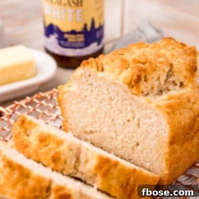 Simple & Delicious Beer Bread 7 A loaf of beer bread on a copper wire rack that has been sliced.