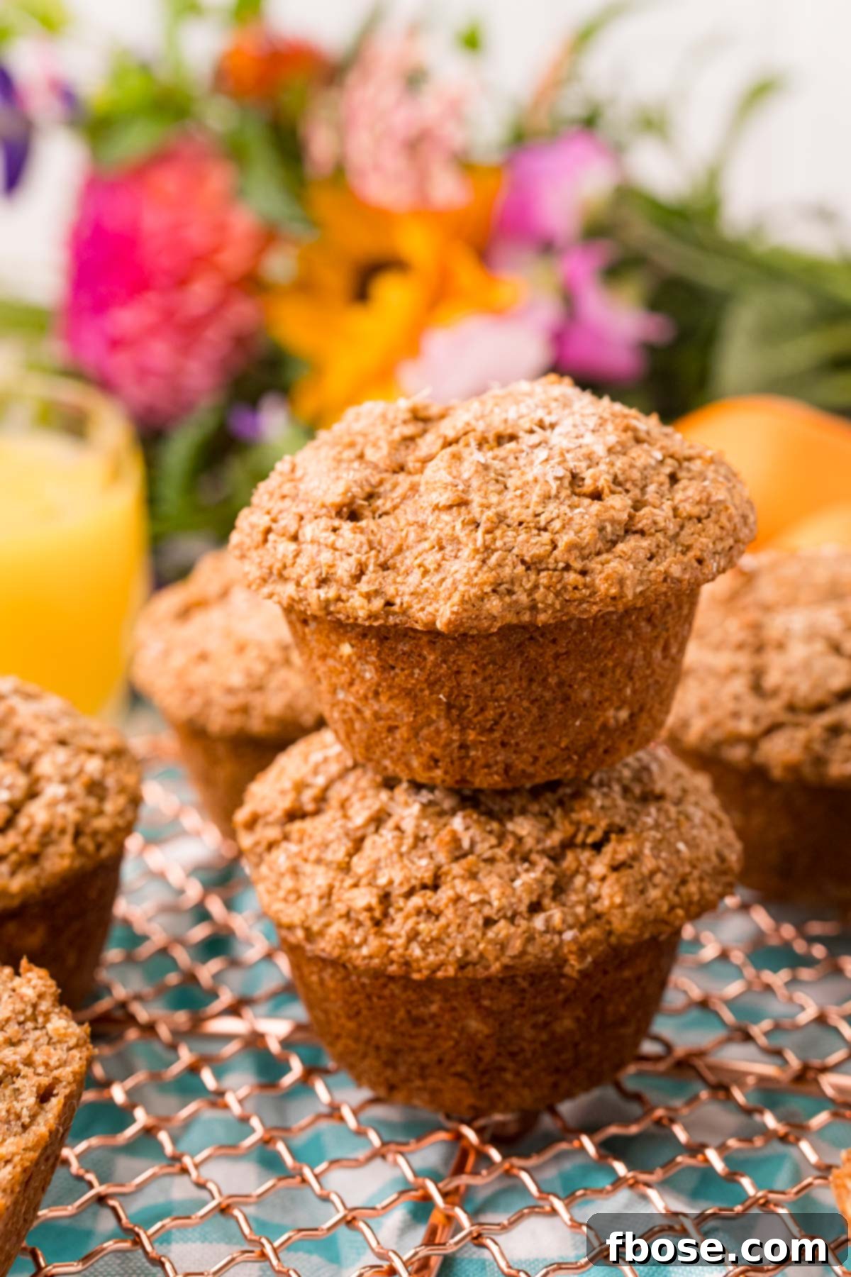 Two bran muffins stacked on top of each other on a wire rack.