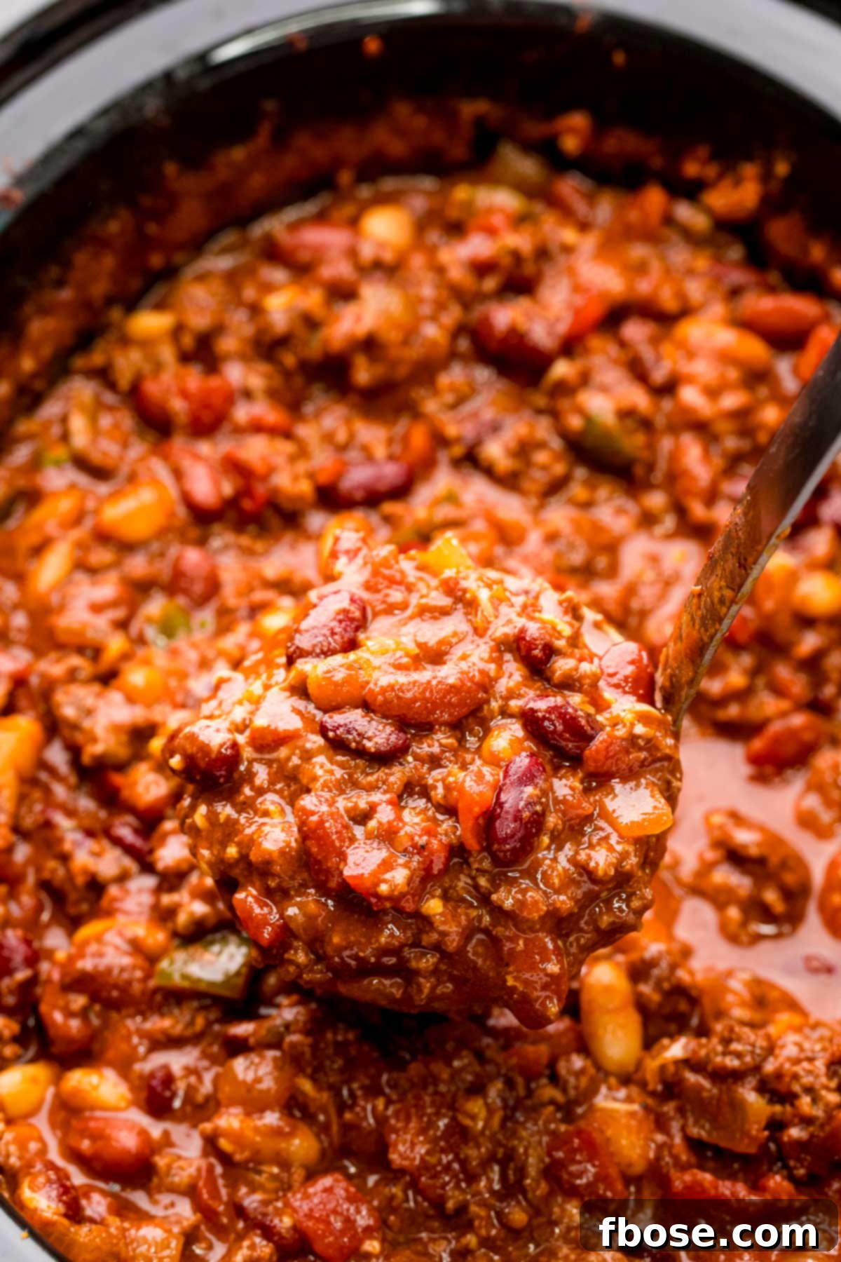 Ultimate Slow Cooker Chili 3 Close-up photo of a ladle serving thick, rich chili from a slow cooker, highlighting the texture and abundance of ingredients.