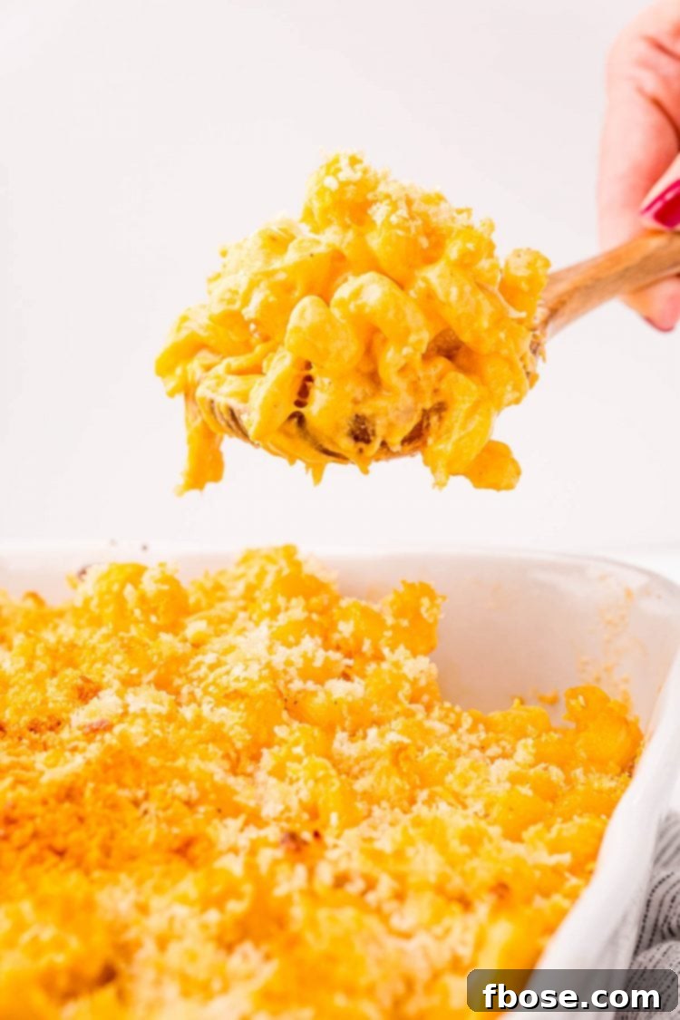 Close up photo of a serving spoon scooping buffalo chicken mac and cheese out of a white casserole dish.