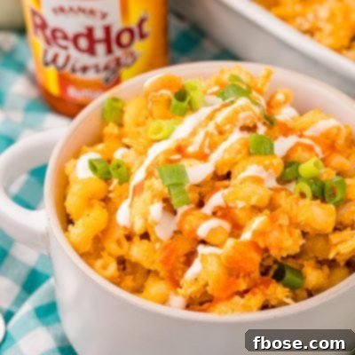 Close up photo of a bowl of buffalo chicken mac and cheese on a teal and white gingham napkin.