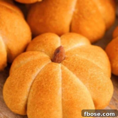 Spiced Pumpkin Feast Rolls 7 Close-up of pumpkin flavored and shaped dinner rolls on a wooden cutting board.