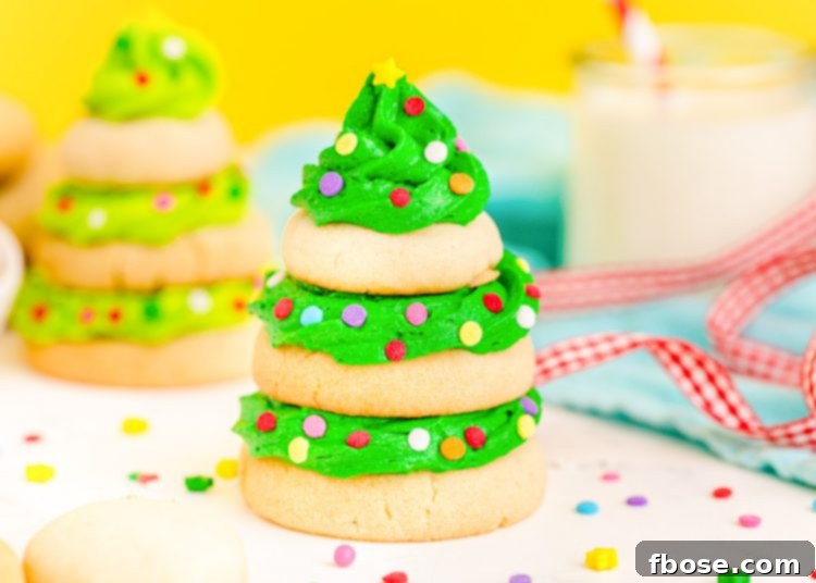 Festive Fir Tree Treats 12 Another close-up shot of a magnificent Christmas tree cookie, formed from stacked sugar cookies and adorned with vibrant green frosting, presented on a white surface with a soft yellow background.