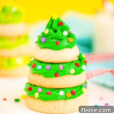 Festive Fir Tree Treats 13 Close up photo of a Christmas tree cookie made with stacked sugar cookies and green frosting on a white surface with a yellow background.