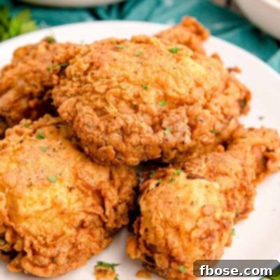 Close up photo of buttermilk fried chicken on a white plate on a teal napkin.