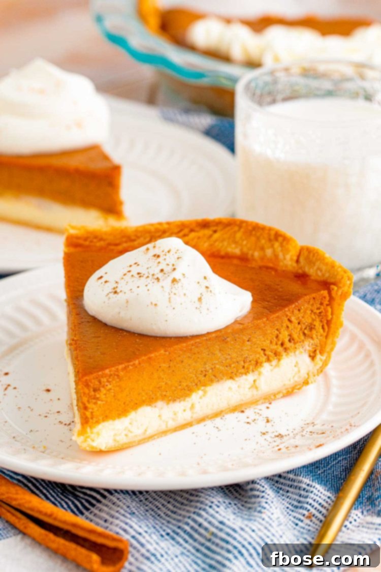 Close up photo of a slice of pumpkin cheesecake pie on a white plate with another slice in the background.