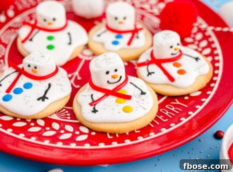 Melty Snowman Cookies 3 A red plate piled high with delightful melted snowman cookies, each uniquely decorated with festive candies and icing details.