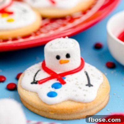 Close up photo of melted snowman cookies on a blue counter with some on a red plate in the background.