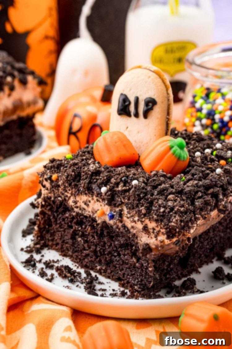 Close up photo of a slice of chocolate Halloween Cake on a white plate on an orange napkin, decorated with ghost peeps and tombstone cookies.