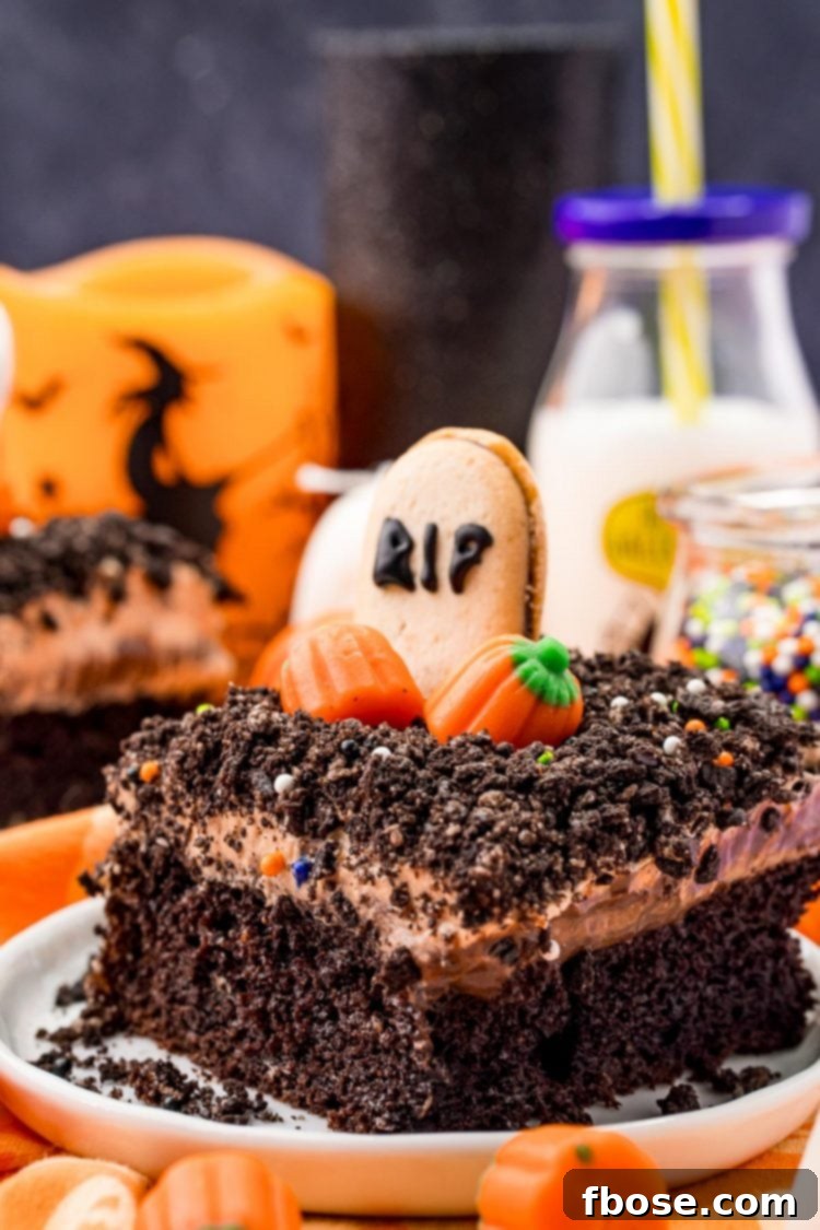 A slice of Halloween dirt cake on a white plate on an orange napkin with Halloween decorations and a bottle of milk in the background.