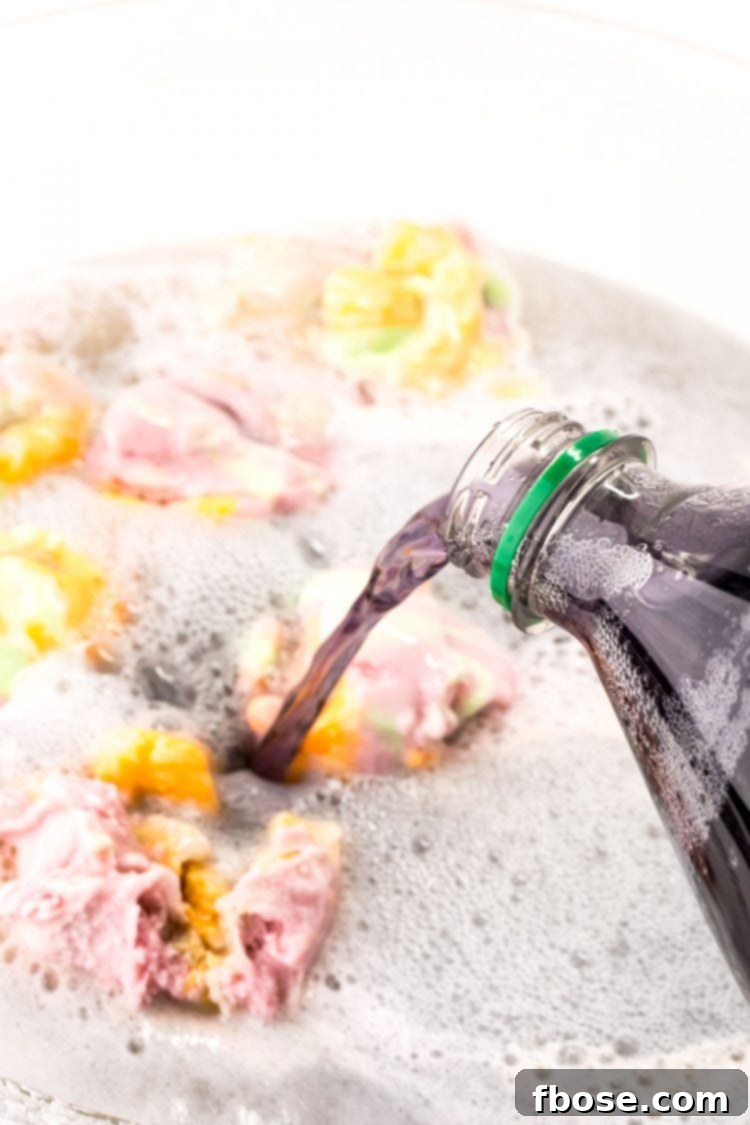 Grape soda being poured into a punch bowl with sherbet and lemonade.