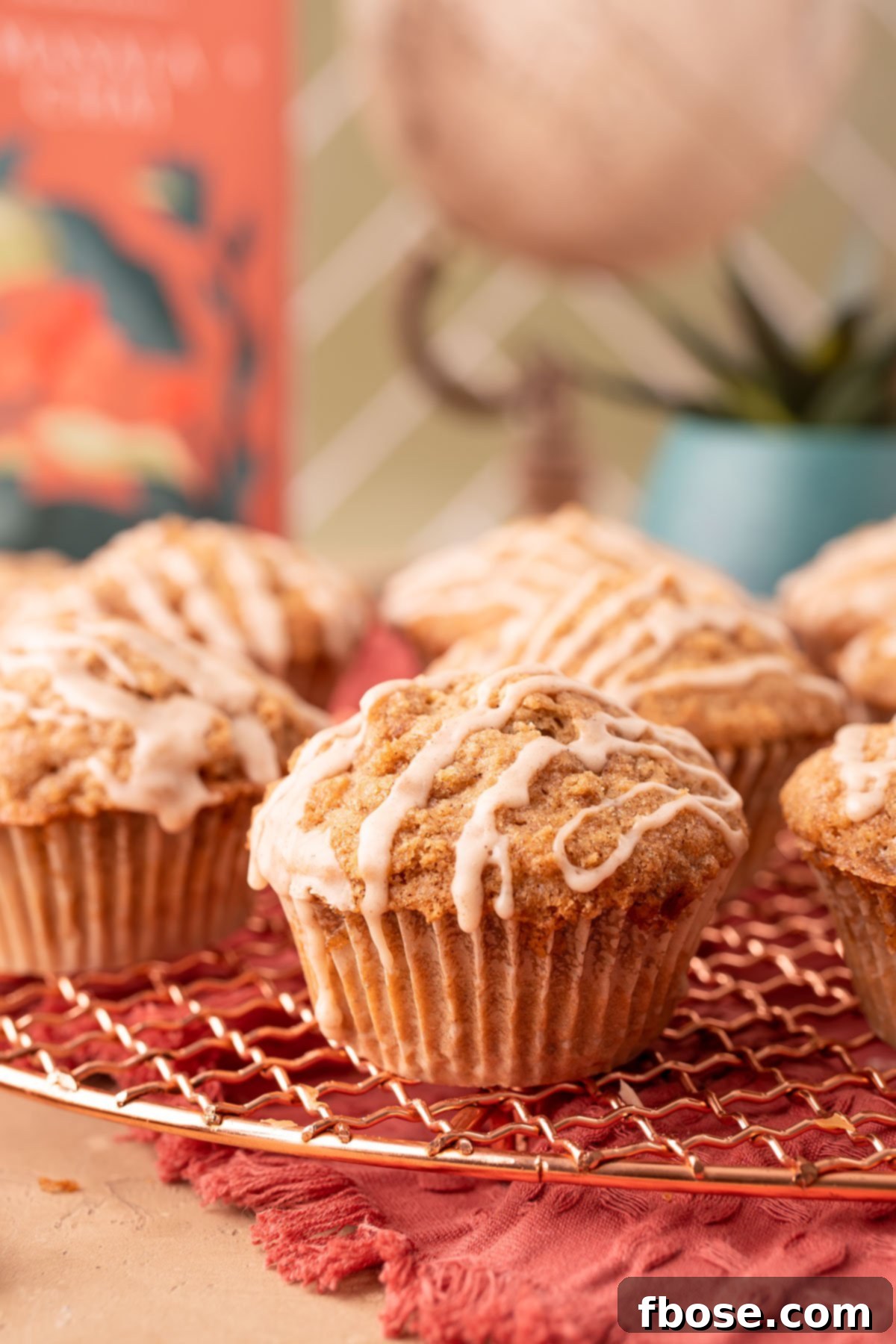 A top-down view of beautifully arranged Vanilla Chai Muffins cooling on a copper wire rack, highlighting their intricate crumble and glaze.