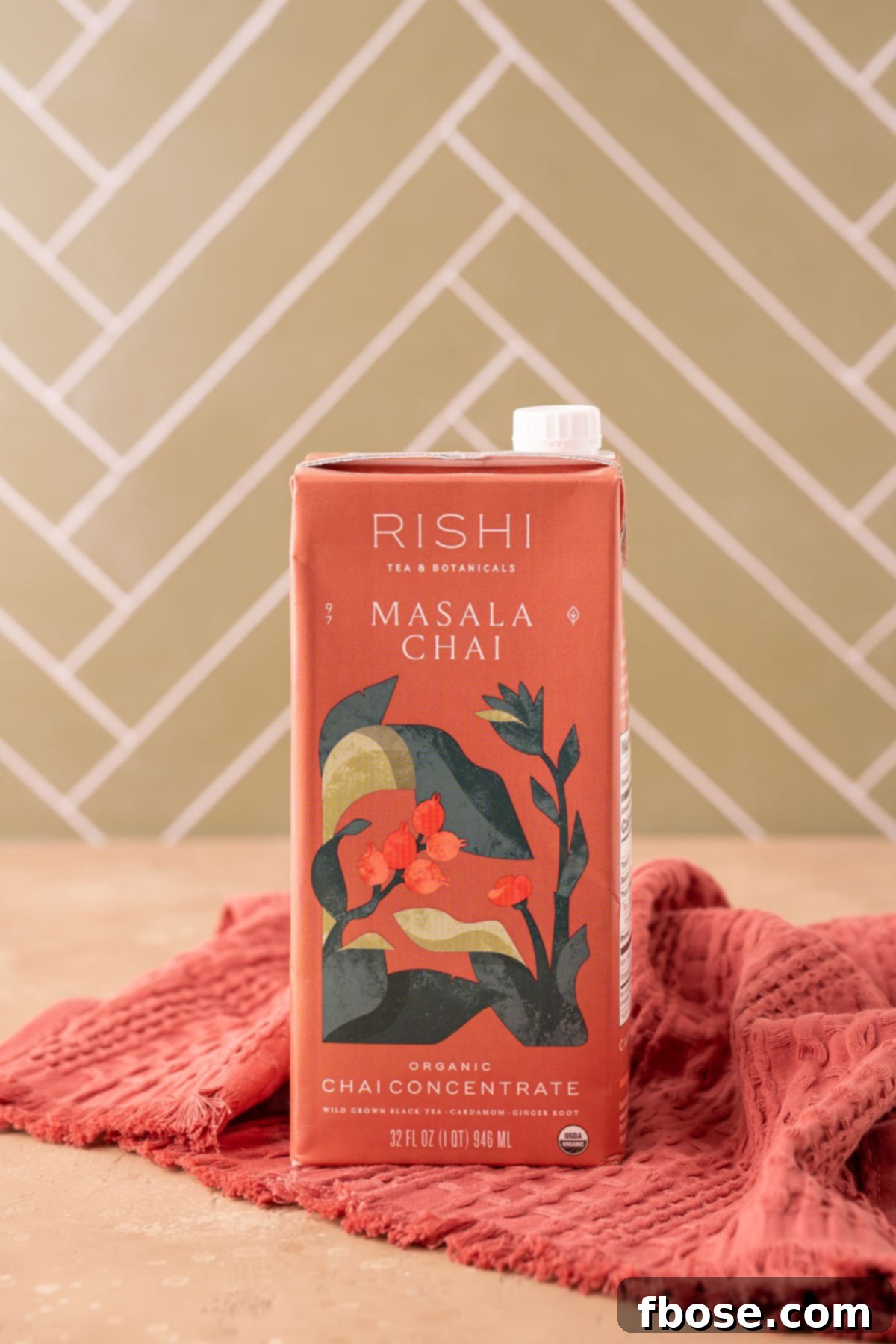 A box of premium chai concentrate rests on a rustic wooden table, emphasizing the quality ingredient used in the recipe.