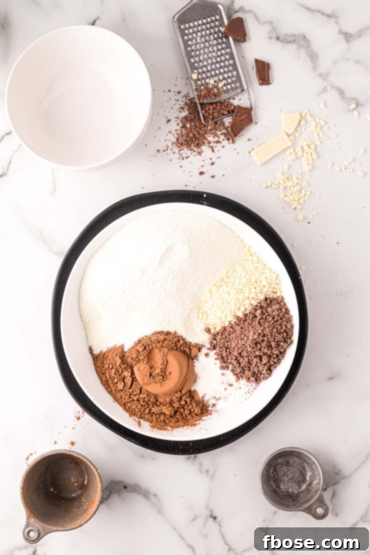 overhead photo of ingredients being added to a mixing bowl to make homemade hot chocolate mix.