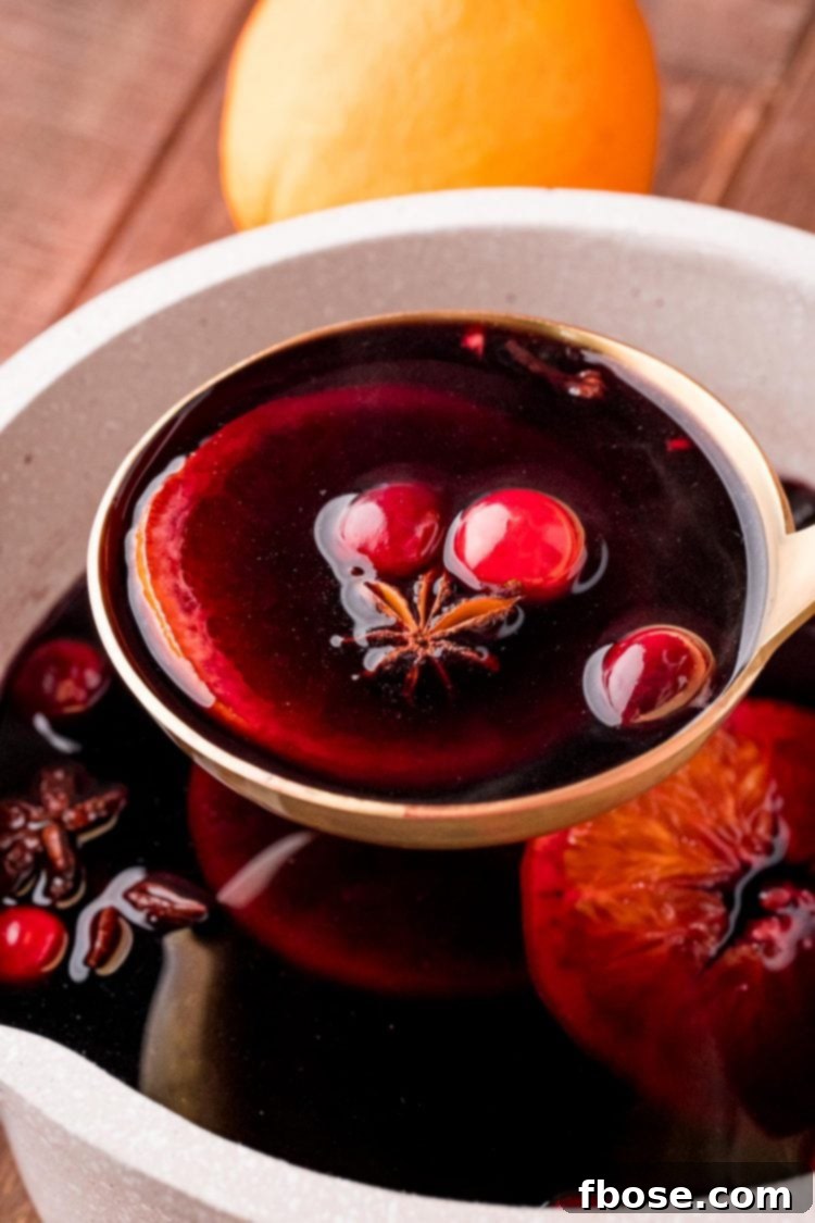 A ladle scooping mulled wine out of a small saucepot.