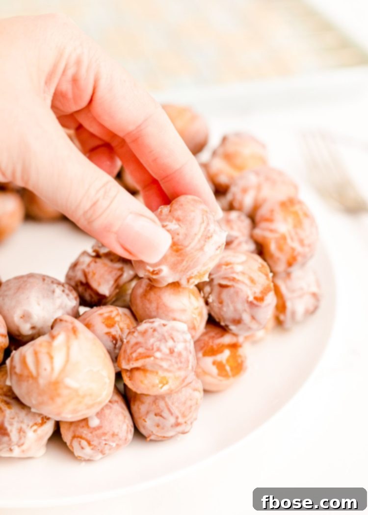 Festive Doughnut Drop Wreath 6 Close up photo of a woman's hand arranging donut holes on a white plate.