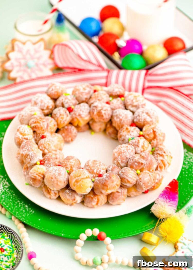 Festive Doughnut Drop Wreath 7 Donut holes arranged on a white plate to look like a wreath with holiday decorations around it.