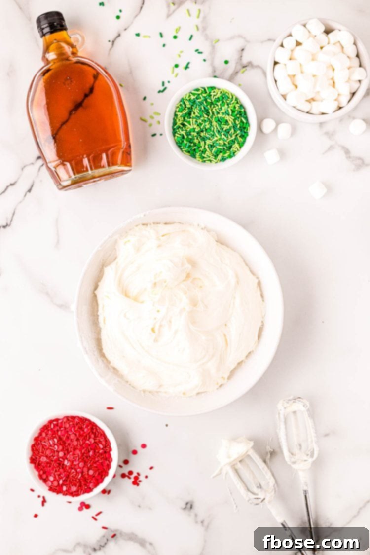 Overhead photo of cream cheese, fluff, and powdered sugar mixed in a white bowl.