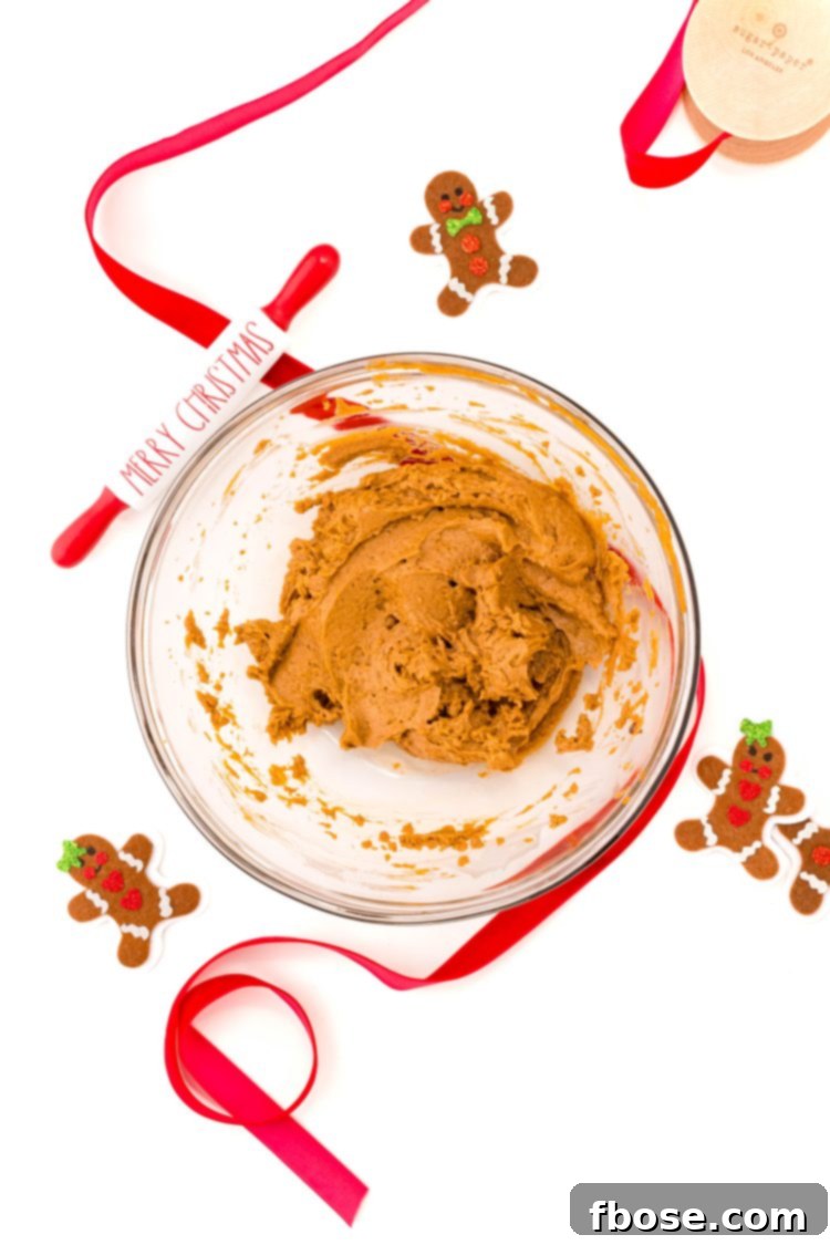 No Bake Gingerbread Cookie Dough 5 Overhead photo of a glass bowl filled with edible gingerbread cookie dough with red ribbon and gingerbread men around it.