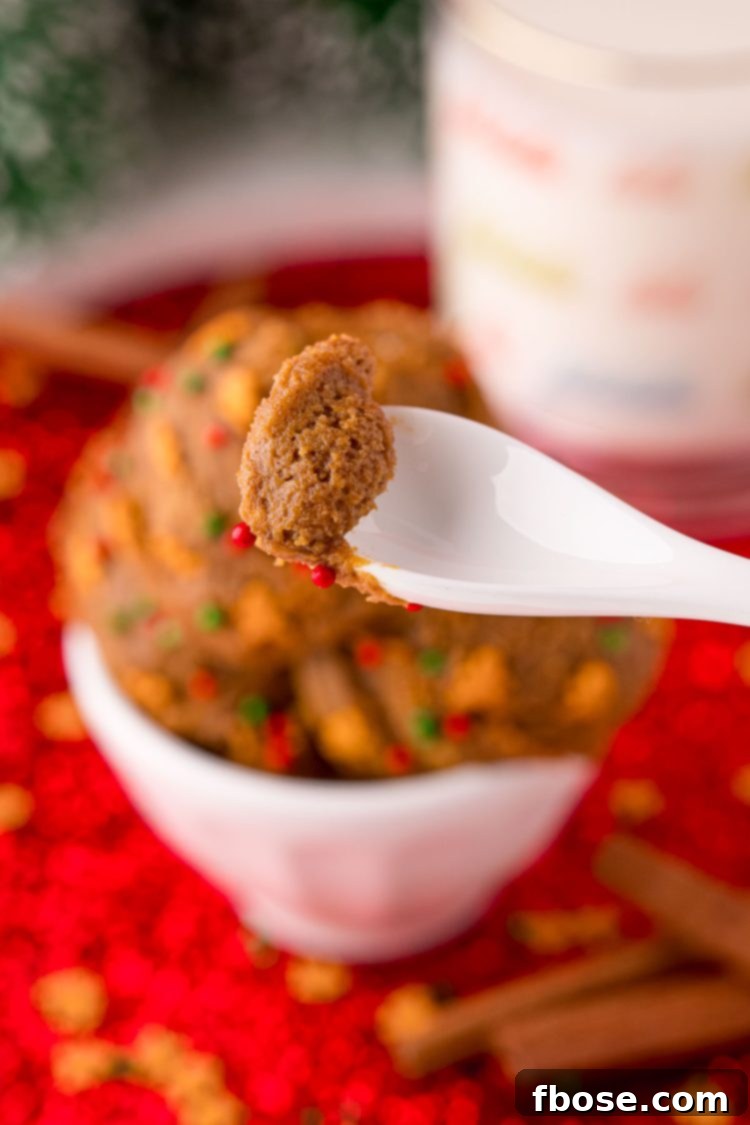 No Bake Gingerbread Cookie Dough 6 A white spoon taking a bite of edible gingerbread cookie dough from a bowl.