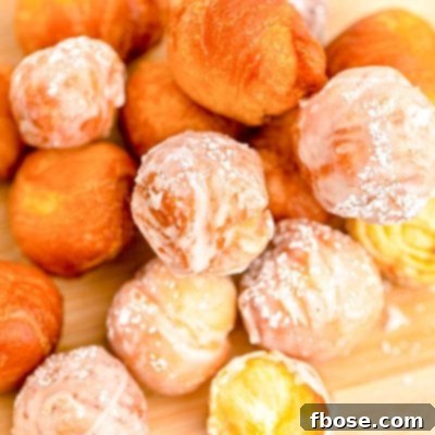 Close up photo of fried donut holes on a wooden cutting board.