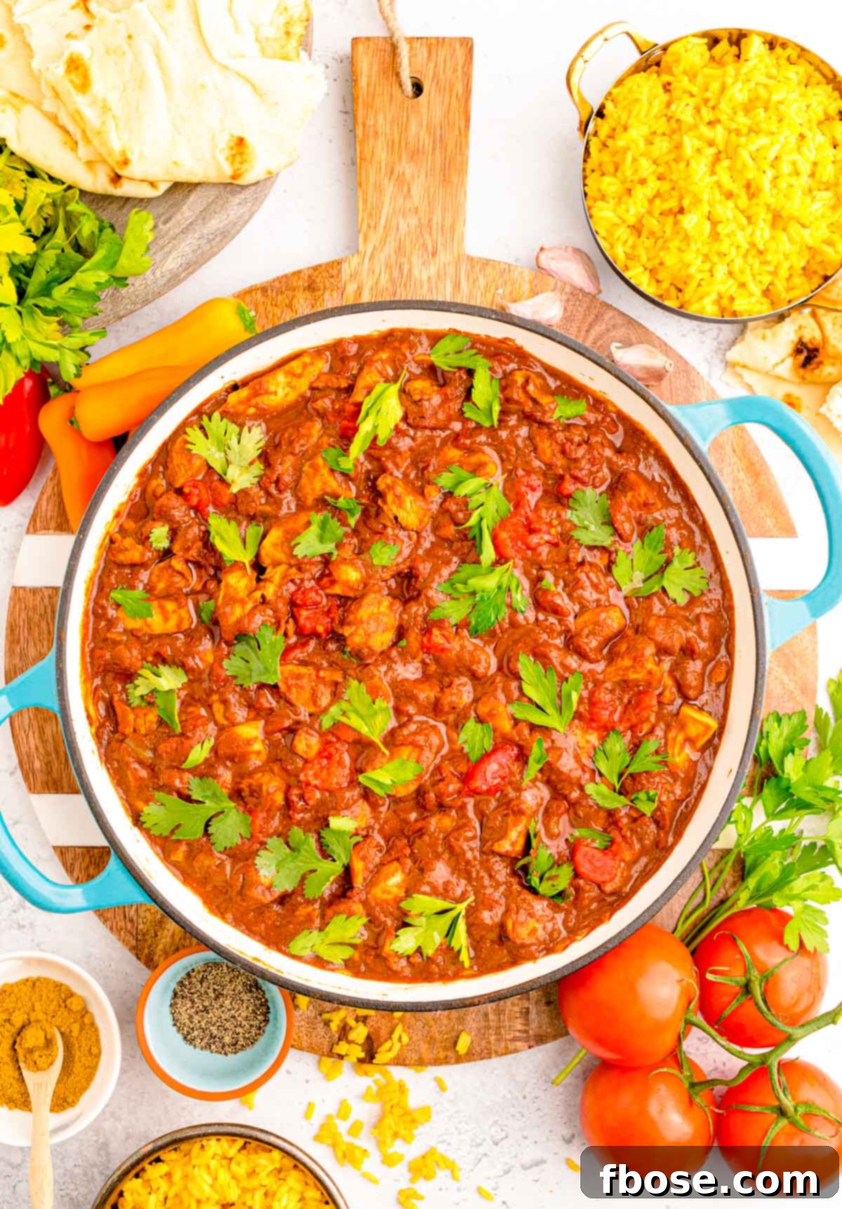 Effortless Madras Curry 2 Overhead photo of a skillet with madras curry in it surrounded by fresh ingredients like cilantro and spices.