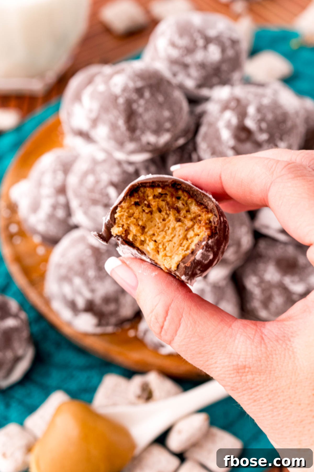 A woman's hand holding a puppy chow truffle with a bite taken from it to the camera.