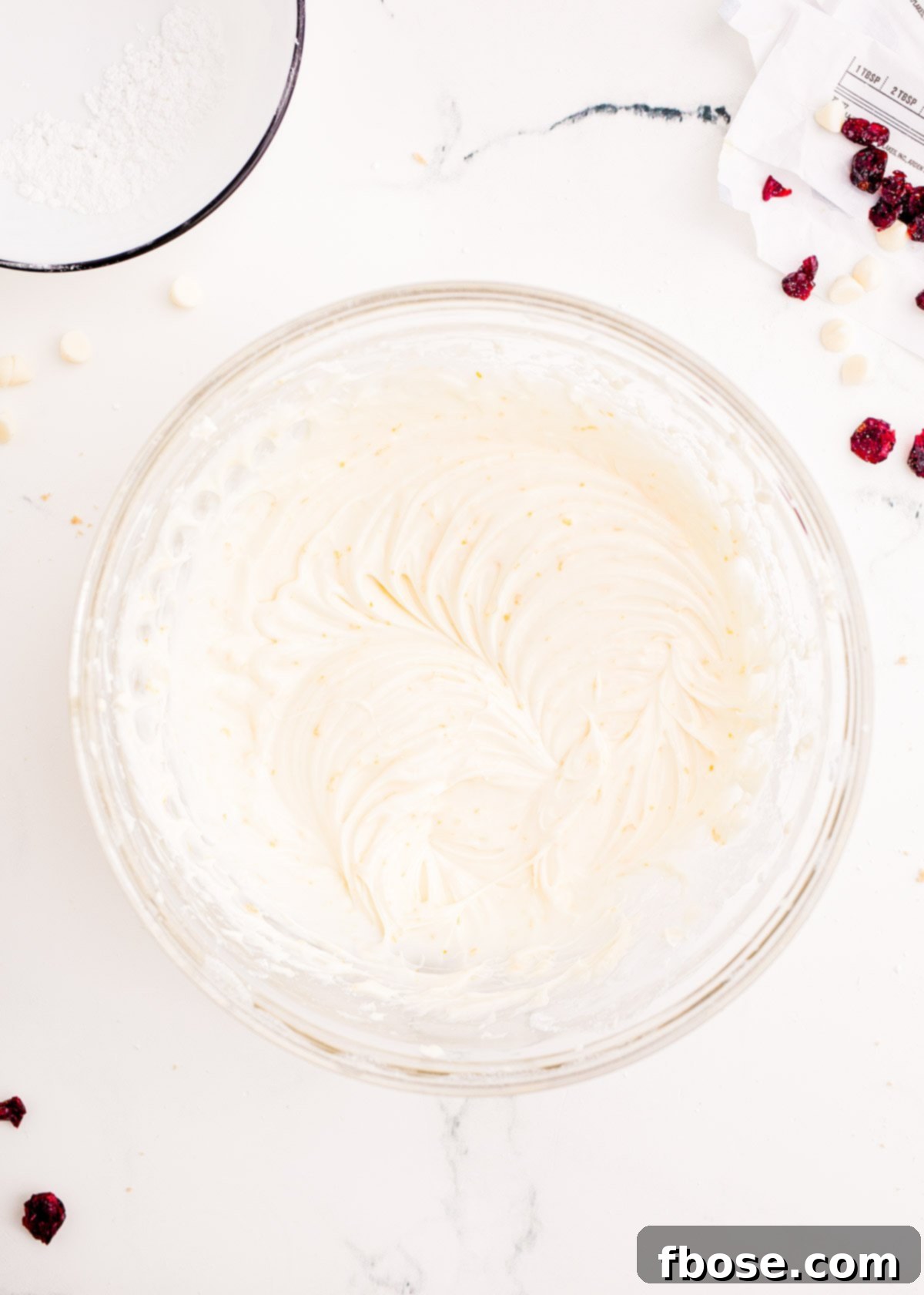 Luxurious cream cheese frosting, perfectly smooth and creamy, prepared in a glass bowl, ready to top the cranberry bliss bars.