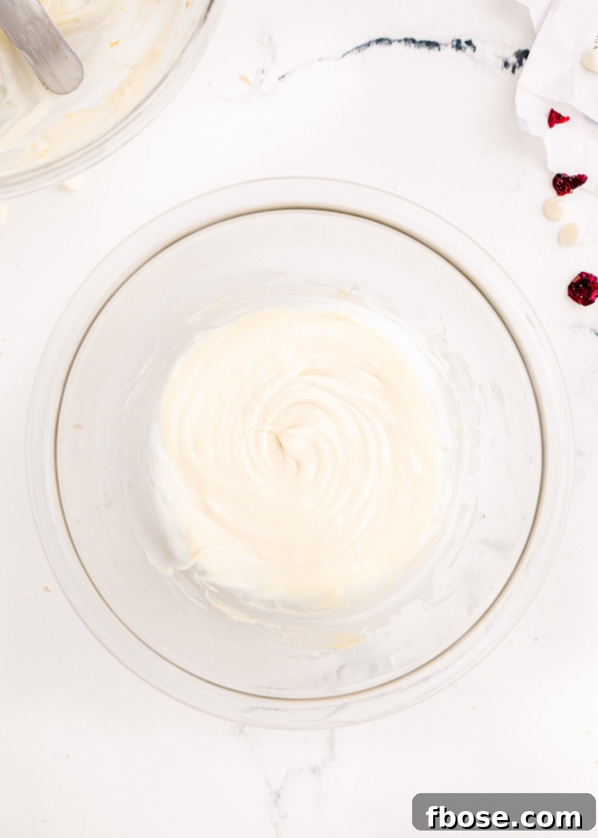 Smooth, melted white chocolate, perfectly prepared for drizzling, rests in a small glass bowl.