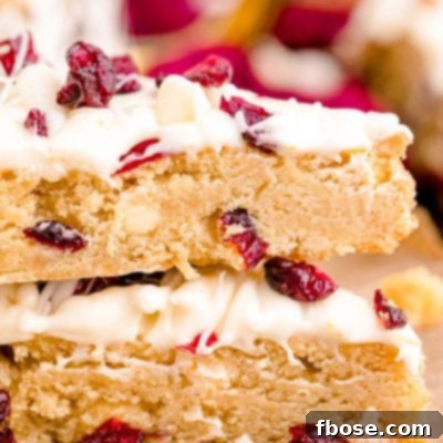 Close up photo of two Starbucks copycat cranberry bliss bars stacked on parchment paper.