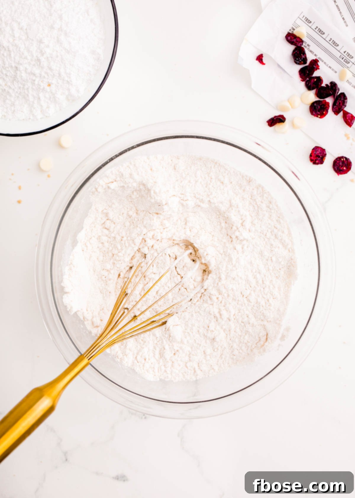 All-purpose flour, cornstarch, baking powder, and salt being thoroughly whisked together in a large glass bowl to create a uniform dry mixture.