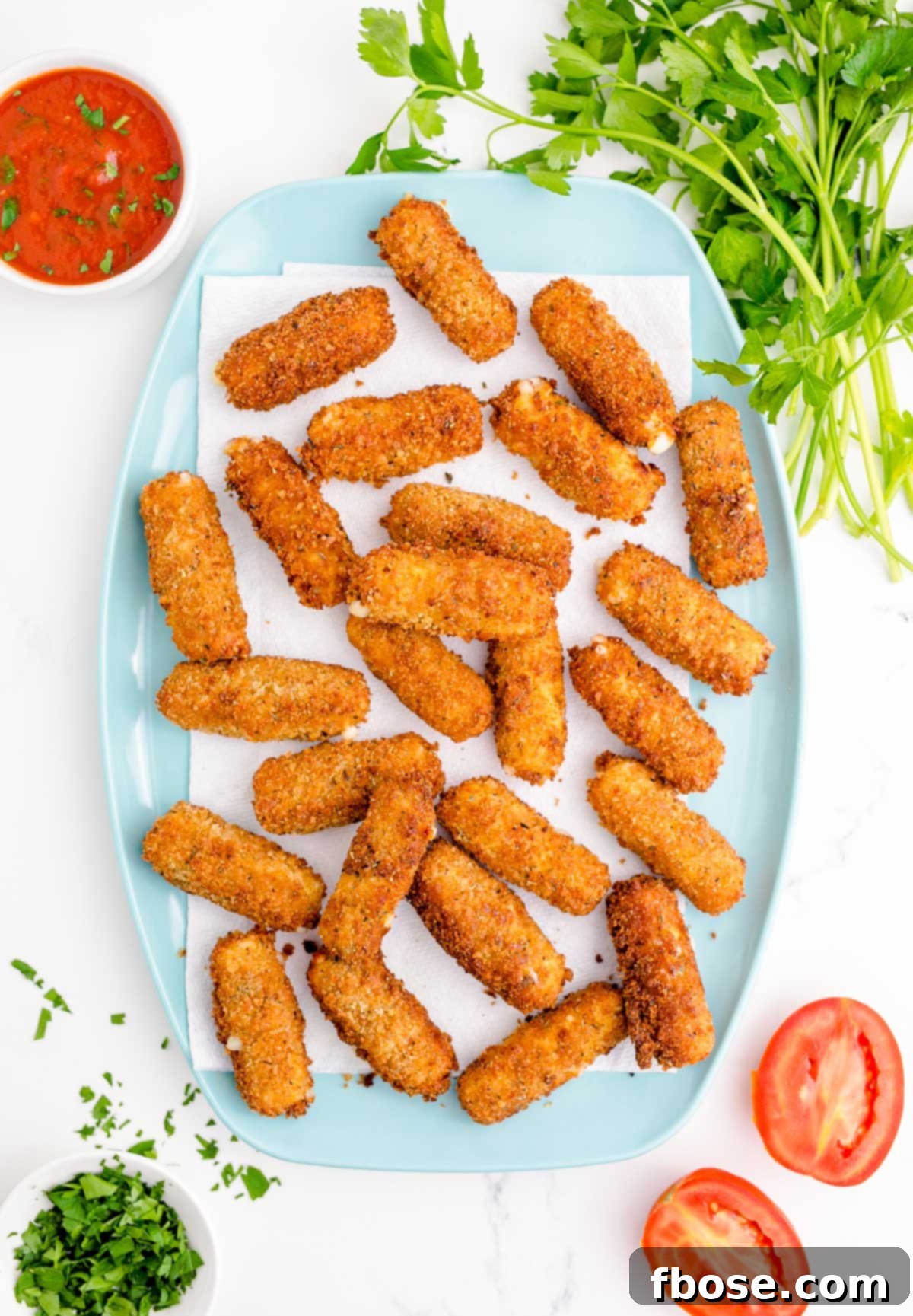 Overhead photo of mozzarella sticks on a paper towel-lined blue plate.