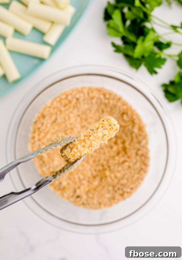 A bread crumb covered mozzarella stick being held over a bowl with tongs.