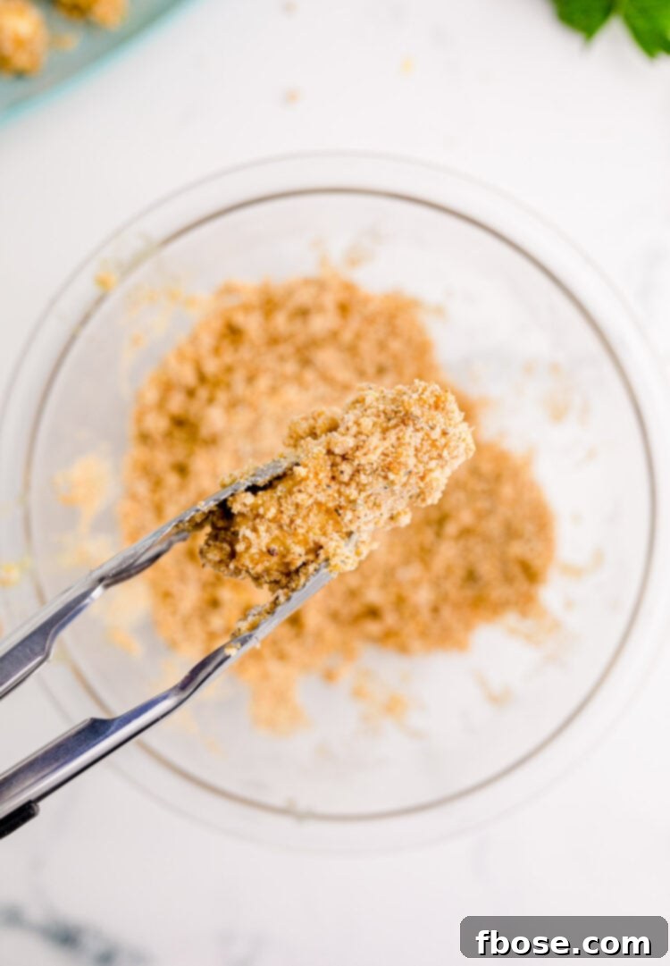 A mozzarella stick coated in bread crumbs ready to be fried.