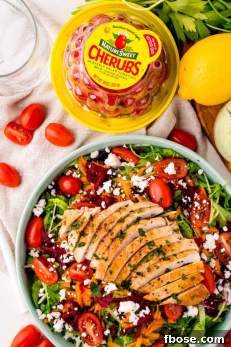 Overhead photo of grilled chicken salad in a teal bowl with a package of NatureSweet Cherubs next to it.