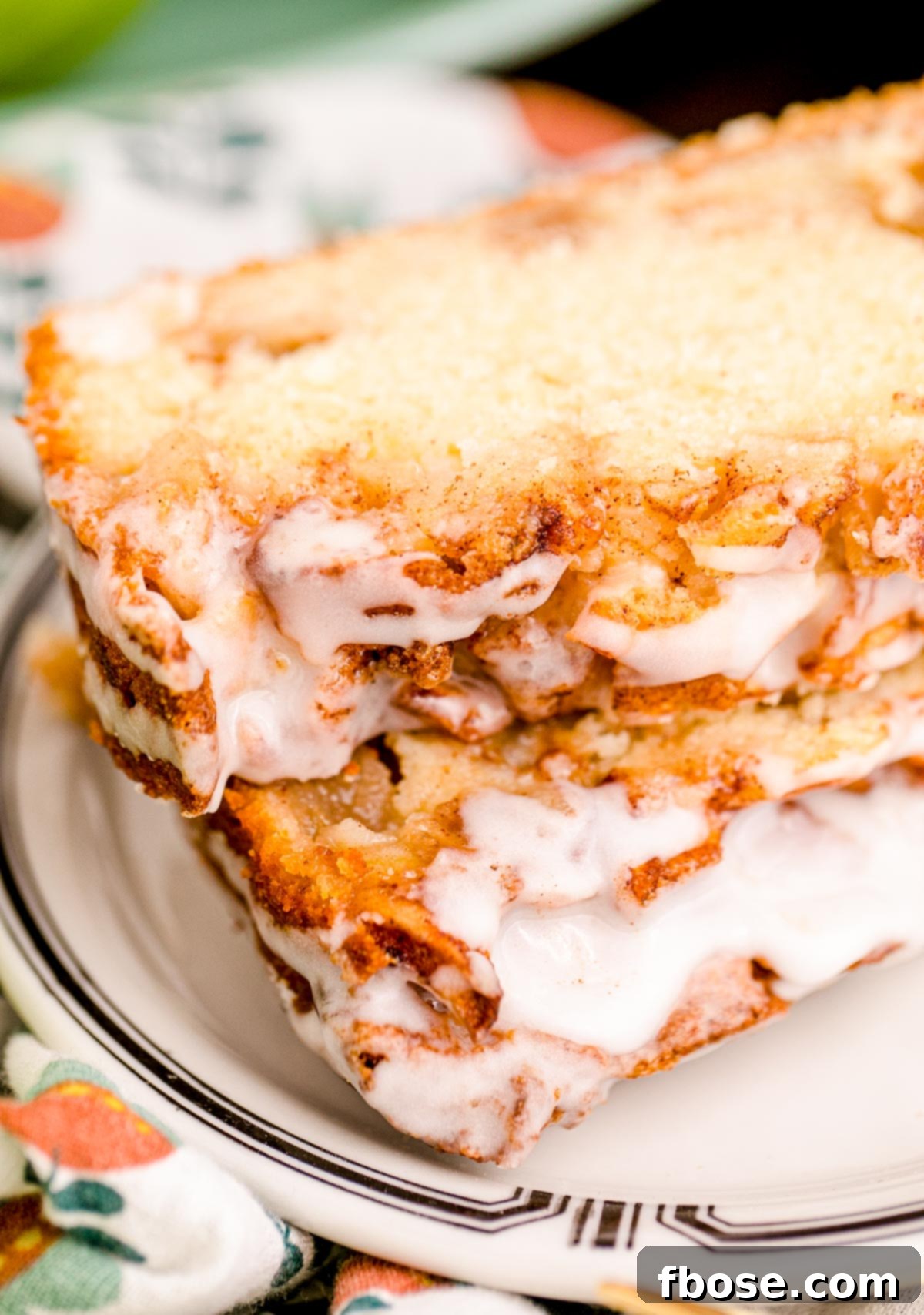Slices of moist apple fritter bread on a white plate, showcasing the apple chunks and cinnamon swirl.