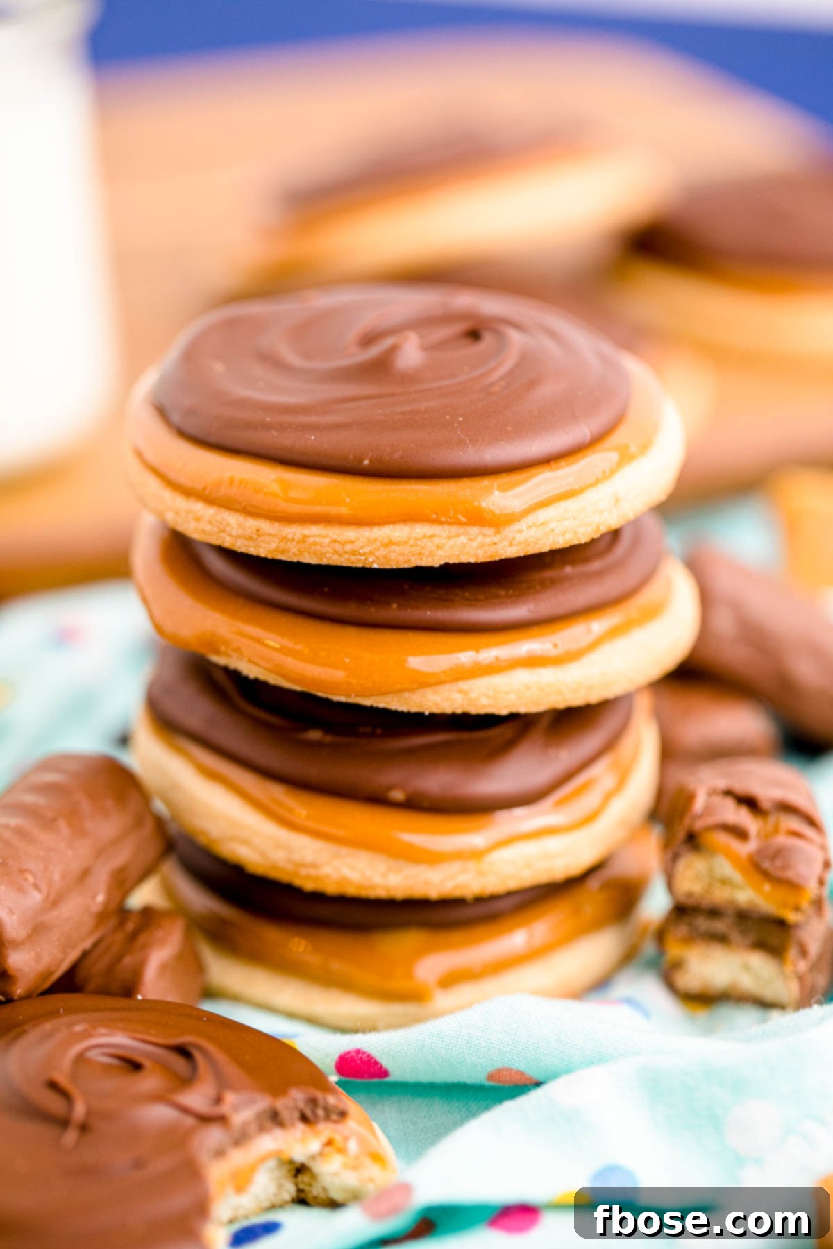 Close up photo of a stack of 4 Twix cookies on a light blue napkin, showcasing the layered perfection.