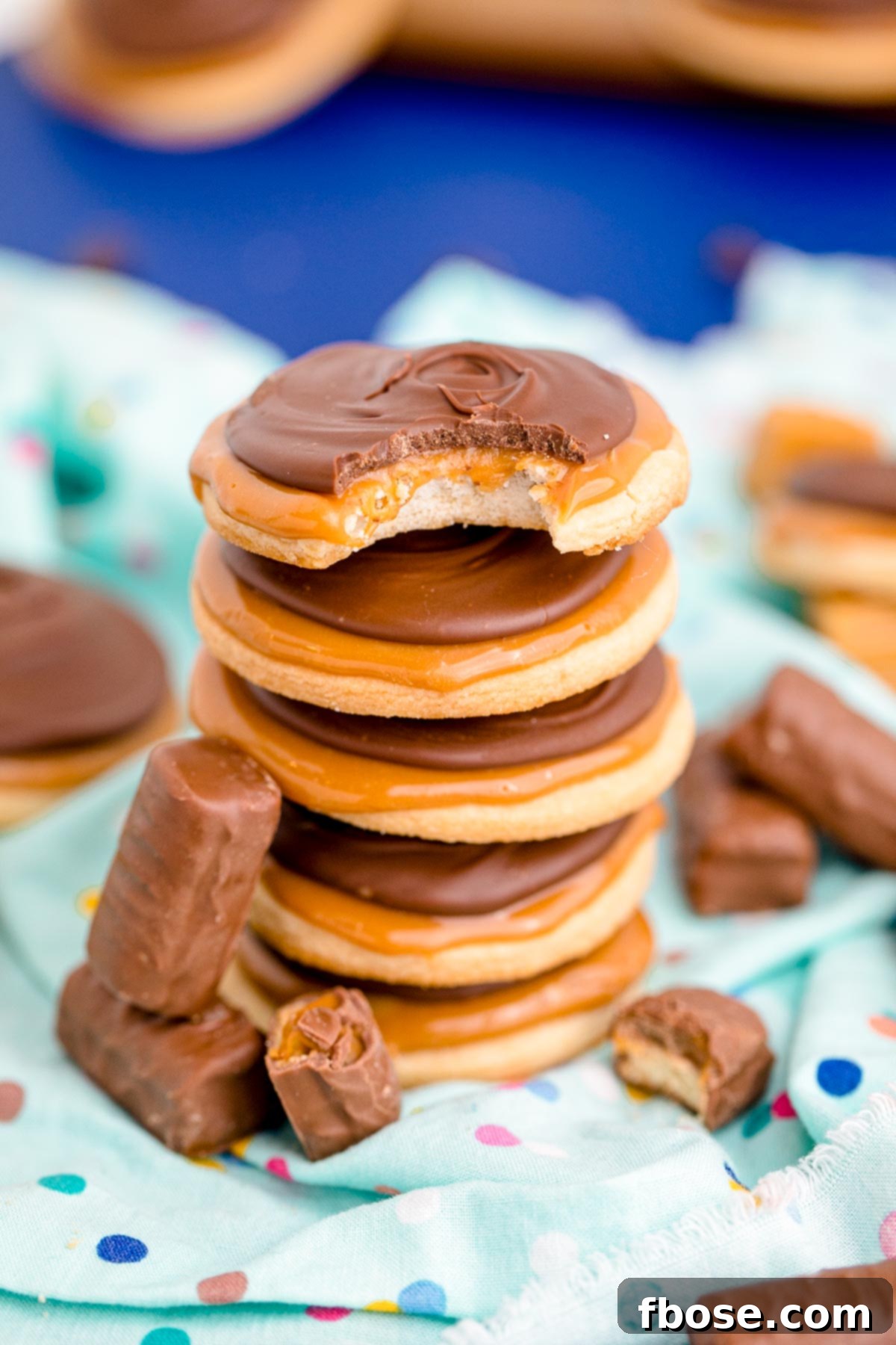 Close up photo of a stack of 4 Twix cookies on a light blue napkin, highlighting the delicious layers.