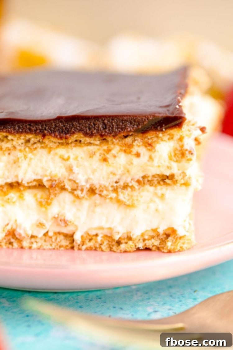 Close up photo of a slice of eclair cake on a pink plate on a blue table.