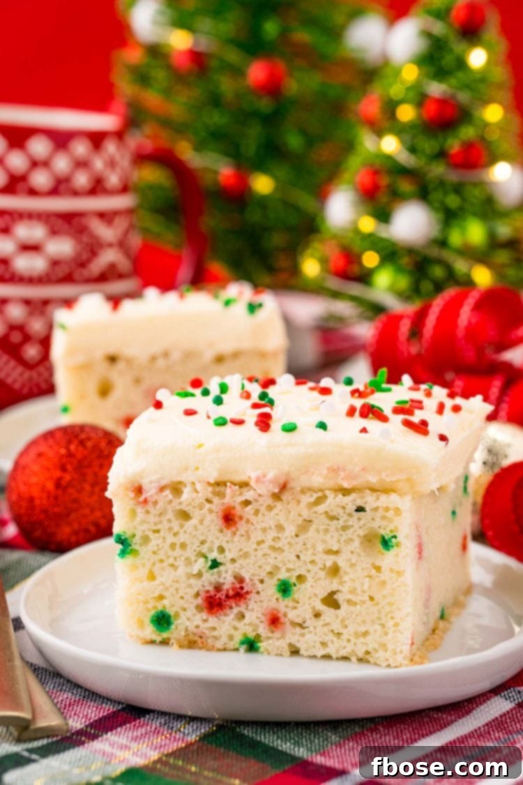 Yuletide Delight 6 A slice of funfetti Christmas cake on a white plate on a holiday napkin with decor in the background.