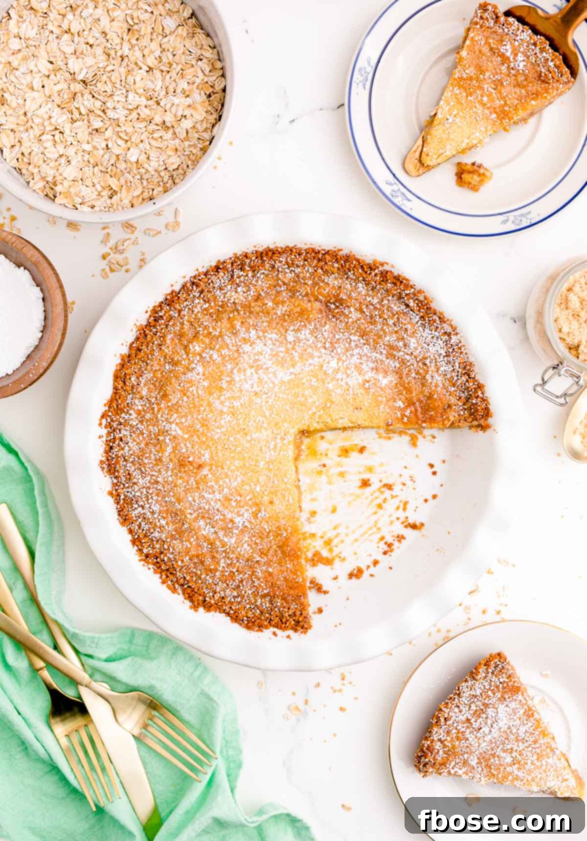 Overhead photo of Milk Bar Pie on a white table with a slice missing, showing its golden-brown top and thick crust.