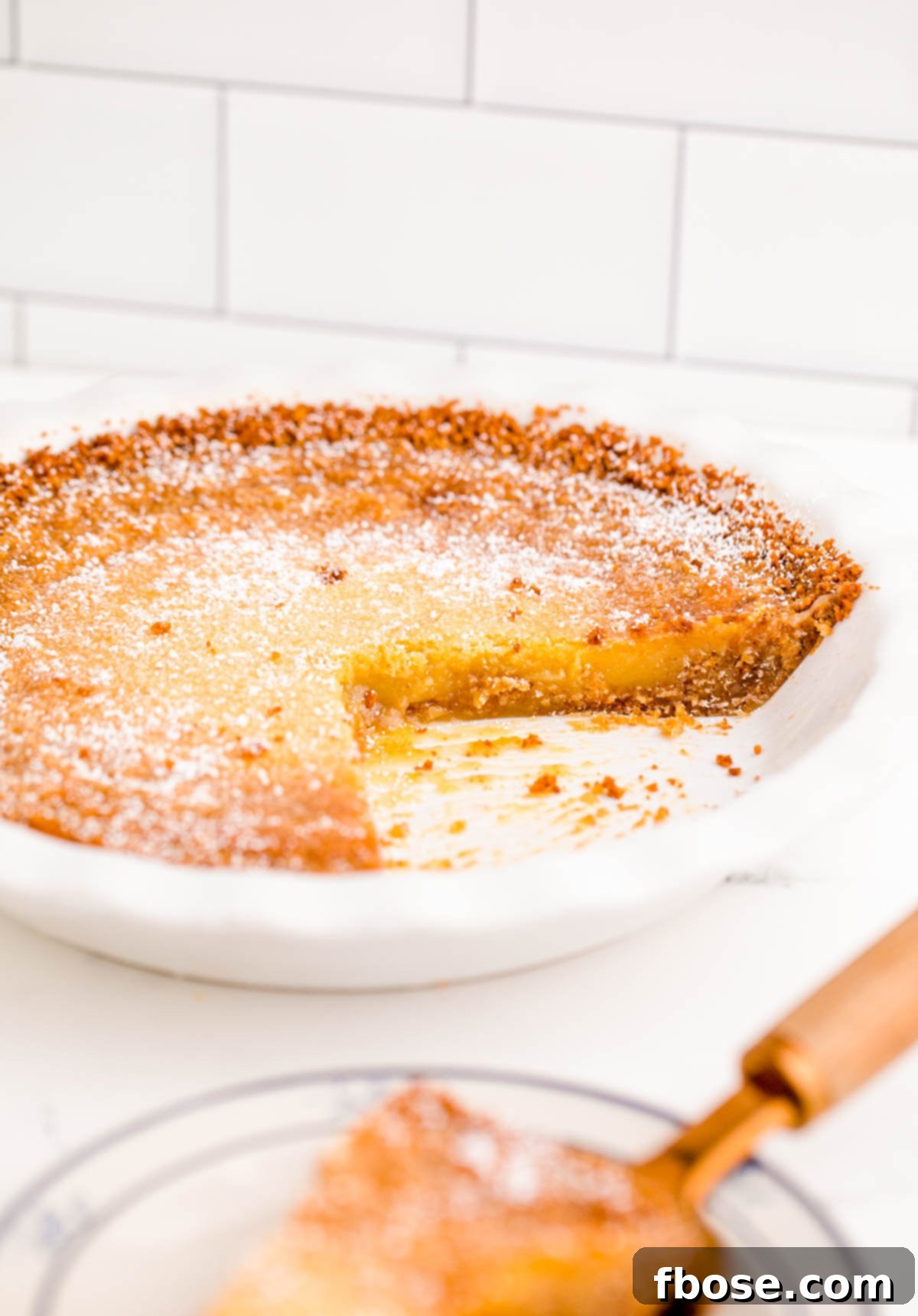 A Milk Bar Pie on a white table with a slice missing, perfectly baked and ready to be enjoyed.