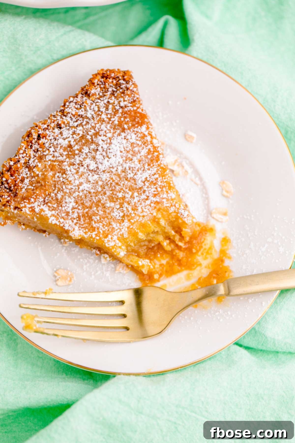 A slice of Milk Bar Pie on a white plate on a green napkin with a fork, showing the creamy filling and crumbly crust.