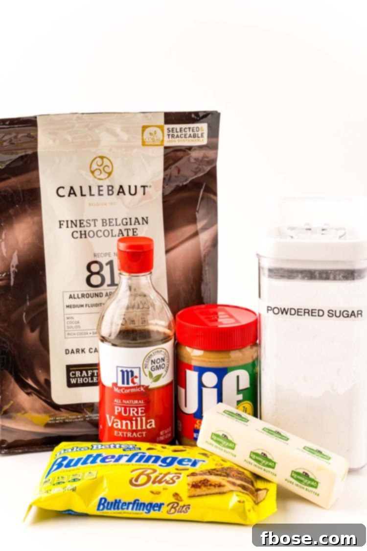 Various ingredients laid out on a white table, ready to make butterfinger balls: peanut butter, butter, powdered sugar, vanilla extract, Butterfinger bits, and chocolate melting wafers.