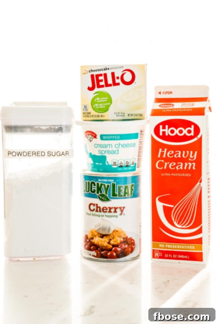 A beautifully arranged flat lay photo displaying all the fresh and packaged ingredients needed to create the easy Cherry Cheesecake Dip, set on a clean white table, ready for preparation.