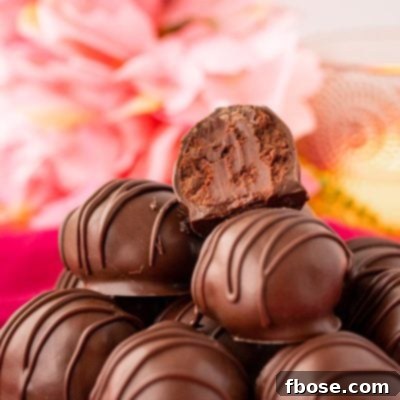 Close up photo of chocolate truffles stacked on a white plate on a pink napkin.